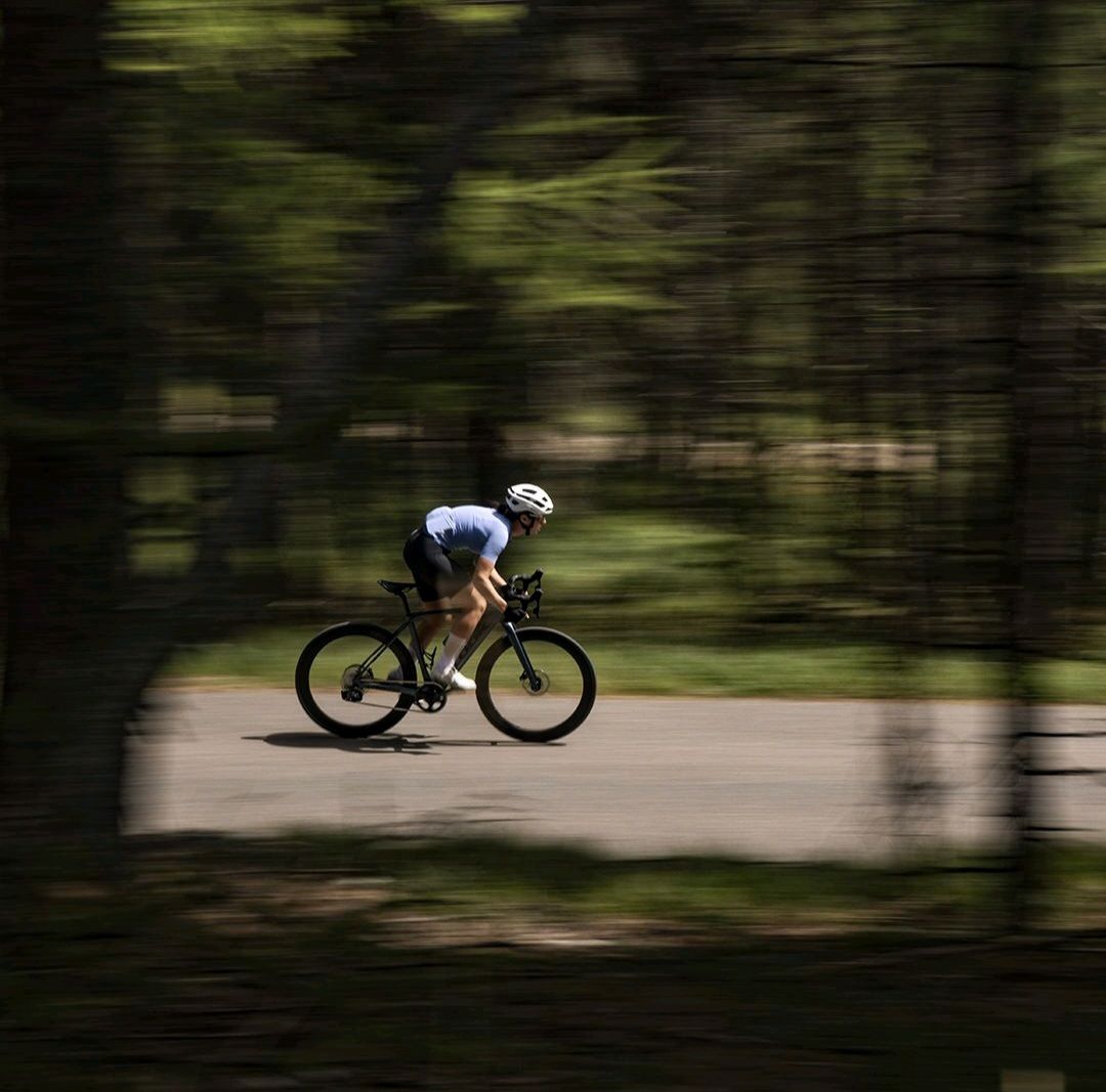 Um ciclista se desloca por uma estrada cercada de árvores
